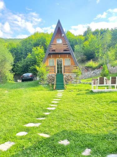 a log cabin with a green door on a grass field at Vilat Pllumaj in Gropat e Selcës