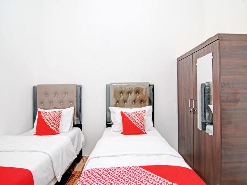 2 bedden in een kamer met rode en witte kussens bij OYO 92946 Dekna Homestay Syariah in Pekanbaru