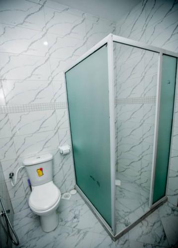 a bathroom with a toilet and a glass shower stall at Snow View Rau Apartments in Moshi