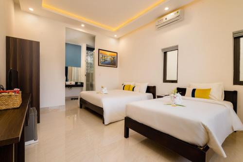a hotel room with two beds and a bathroom at 5 Coconut Villa in Hoi An