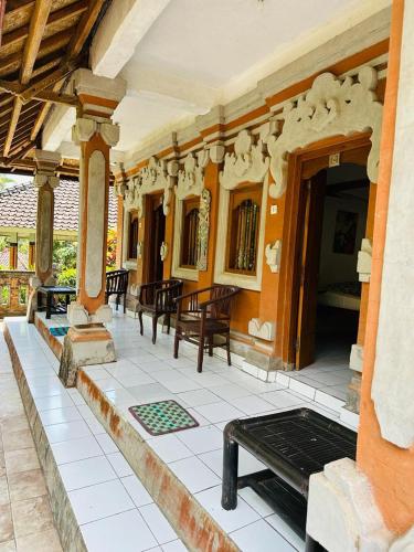a porch of a house with tables and chairs at Pondok Wisata Grya Sari in Banjar