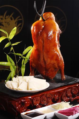 a roasted chicken on a plate next to cheese at Peony Hotel in Dubai