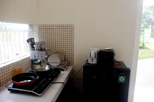 a kitchen with a counter with a stove and a microwave at Privat Homestay Malang Oz HK 39 in Dau