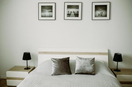 タルヌフにあるApartament Magnolia -centrumのベッドルーム1室(壁に3枚の写真が飾られたベッド1台付)