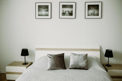 a bedroom with a bed with three pictures on the wall at Apartament Magnolia -centrum in Tarnów