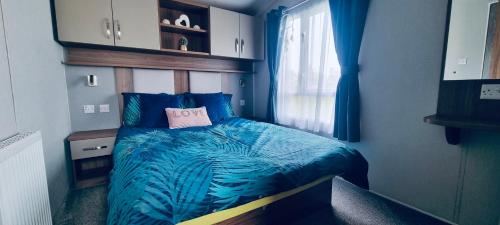 1 dormitorio con 1 cama con edredón azul y ventana en RJ Luxury Caravan Hire With Hot Tub, en Tattershall