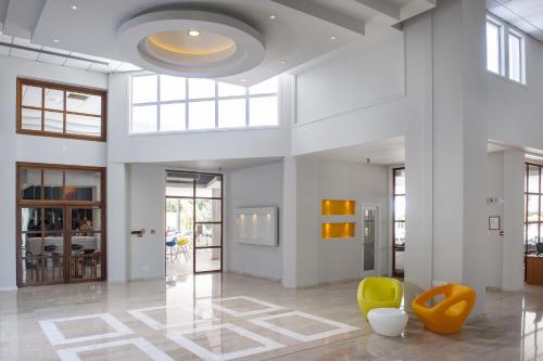 a large white room with yellow chairs and a ceiling at Mayfair Hotel in Paphos City