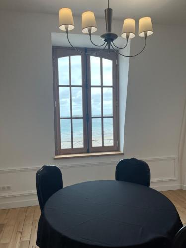 a dining room with a black table and a window at Le Royal XIX Dinard vue mer luxe in Dinard