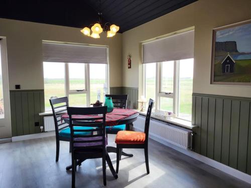 a dining room with a table and chairs and windows at Sibbu Hús in Brjansstadir