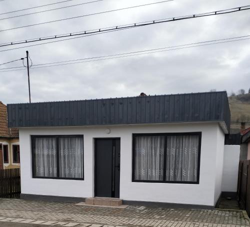 a white house with a black roof at Kub A in Sărmaş