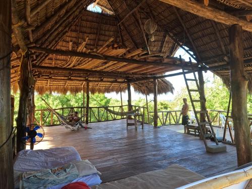 a large wooden deck with a hammock in a hut at Palapa Hostel in Transito