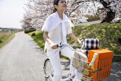 a woman riding a bike with a basket at Kamo Residences by Reflections in Kyoto