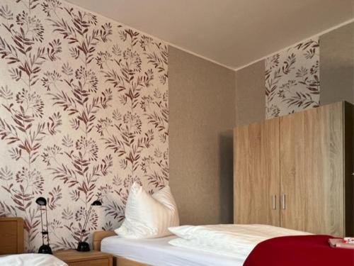 a bedroom with a wall with a floral wallpaper at Ferienwohnung Landlust - ideal für Hundefreunde und Monteure, free WLAN & Parken, Smart-TV in Uebigau