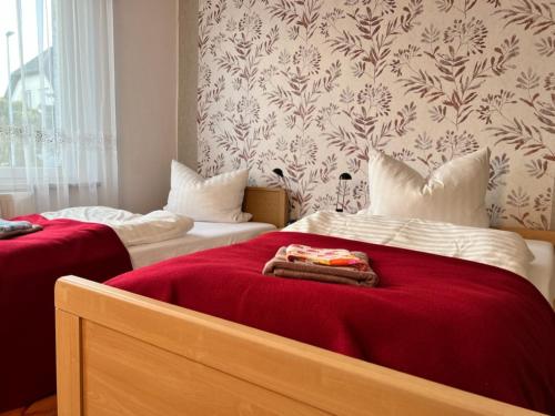 a bedroom with two beds with red sheets and a wallpaper at Ferienwohnung Landlust - ideal für Hundefreunde und Monteure 