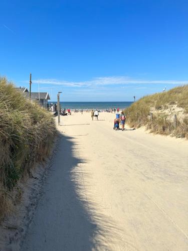 un camino de tierra junto a una playa con gente en ella en Neptunus Appartementen, en Bergen aan Zee