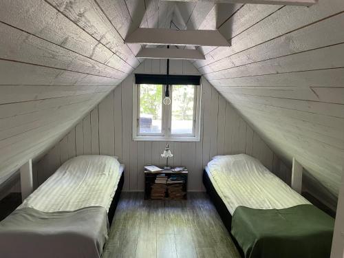 2 Betten in einem Dachzimmer mit Fenster in der Unterkunft Bokis - Modern Forest Cottage in Brösarp