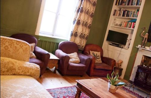 a living room with a couch and chairs and a tv at The Old School House in Céaucé