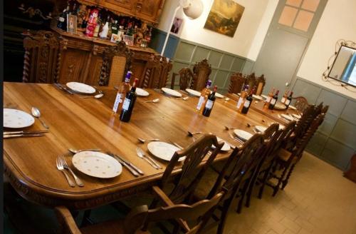 una larga mesa de madera con botellas de vino. en The Old School House, en Céaucé