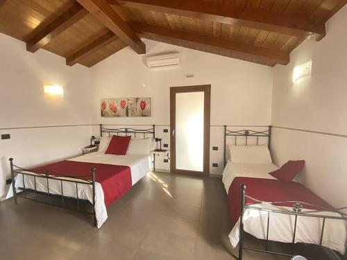 1 dormitorio con 2 camas con sábanas rojas y puerta de entrada en Carpe Diem Countryhouse, en Cesarolo