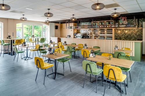 a restaurant with wooden tables and yellow chairs at Hoeve de Bongerd in Beesel