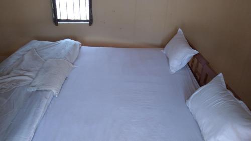uma cama com lençóis brancos e almofadas num quarto em Jaisalmer Safari Base & Camp em Khuri