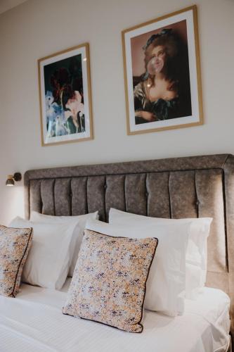 a bed with white pillows and pictures on the wall at Pearl Apartel in Volos
