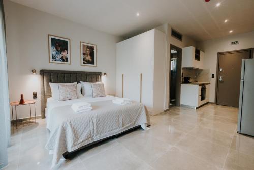a bedroom with a large white bed and a kitchen at Pearl Apartel in Volos