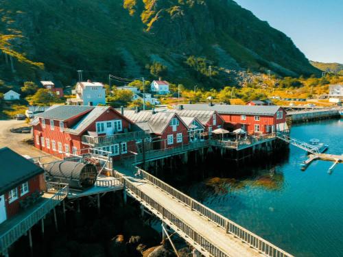 a town next to a body of water with a mountain at Kræmmervika Havn in Ballstad