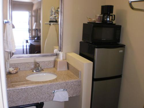 TV y baño con lavabo y microondas. en Executive Inn Mojave, en Mojave