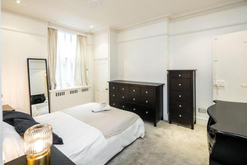 um quarto com uma cama, um espelho e um piano em Spacious 1 bedroom / Gloucester Road / Harrods em Londres