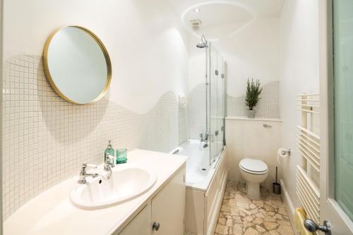 uma casa de banho com um lavatório, um espelho e um WC. em Spacious 1 bedroom / Gloucester Road / Harrods em Londres