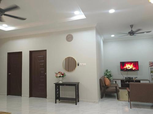 a living room with a fire on the wall and a tv at Inara Homestay Besut in Jertih