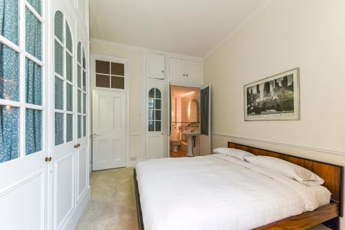 a white bedroom with a bed and a window at HydePark Queens Gate Apt in London