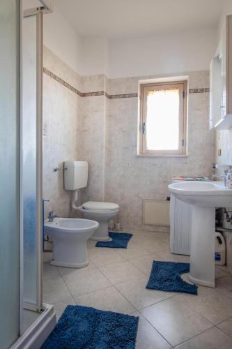 a bathroom with two sinks and a toilet and two rugs at Zion Mare in Soverato Superiore