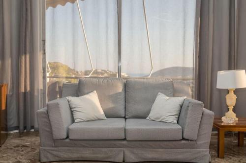 a couch with pillows in a living room with a window at Saronicos Gulf View in Anavissos in Anavissos