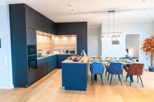 una cocina con armarios azules y una mesa con sillas en CABANA - TheView - 10th Floor - Terrasse - Waterfront - Hafenviertel, en Oldenburg