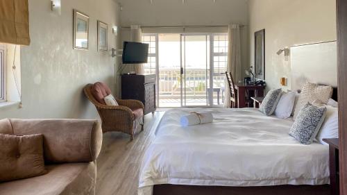 a bedroom with a large white bed and a couch at Sir Roys at the Sea in Port Elizabeth