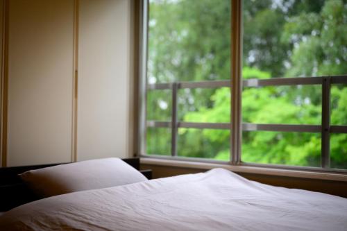 a bedroom with a bed and a large window at 円山山荘 Maruyama villa 自然と調和し和の美を感じる岡山市内屈指の豪邸宿 supported by COCOSTAY in Okayama