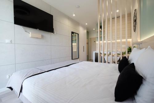 a bedroom with a large white bed with a flat screen tv at Apartamenty Centrum in Białystok