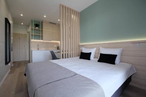 a bedroom with a large white bed with black pillows at Apartamenty Centrum in Białystok