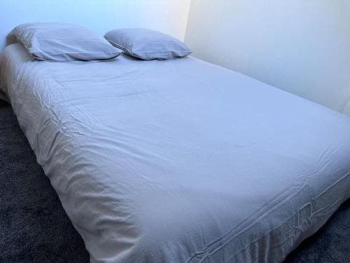 uma cama branca com duas almofadas em cima em Chalet Laguiole Aubrac em Laguiole