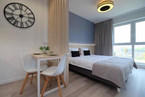 a bedroom with a bed and a table and a clock at Apartamenty Centrum in Białystok