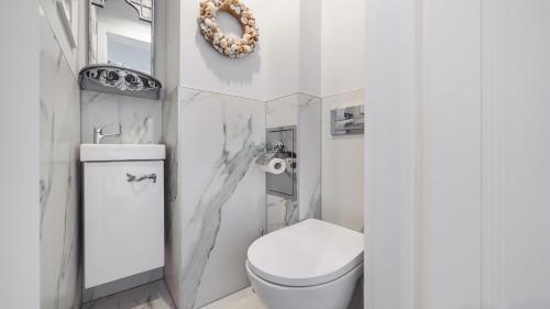 bagno bianco con servizi igienici e specchio di Apartamenty Sun & Snow Hel Centrum a Hel