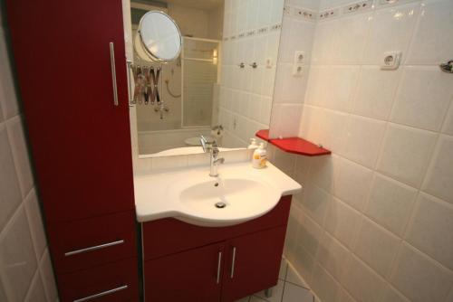 een badkamer met een witte wastafel en een spiegel bij Grömitz- Center I App 322 inkl WLAN in Grömitz
