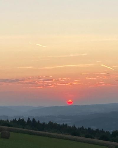 a sunset with the sun setting over the mountains at Stasiówka Gospodarstwo Agroturystyczne in Gogołów
