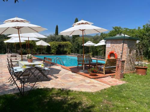 une terrasse avec des parasols et une cheminée à côté d'une piscine dans l'établissement Agriturismo Podere Marchiano, à Larciano