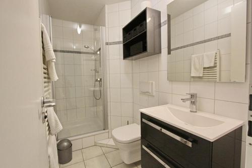 La salle de bains est pourvue de toilettes, d'un lavabo et d'une douche. dans l'établissement Residenz am Kurpark App 10 inkl WLAN, à Grömitz