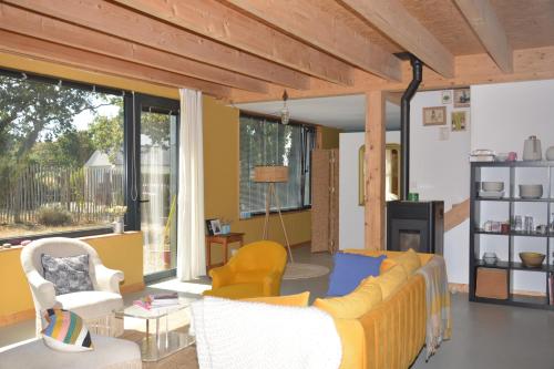 een woonkamer met een gele bank en stoelen bij Le charme du bois - 8 à 10 personnes- Maison entière in La Turballe