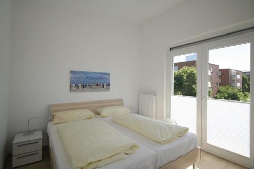 um quarto branco com uma cama e uma grande janela em Wiesengrund 12-14 Whg 17 inkl WLAN em Grömitz