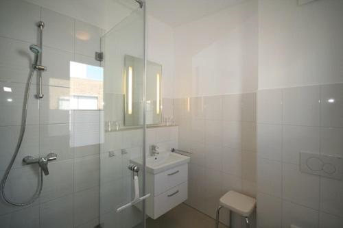 uma casa de banho branca com um chuveiro e um lavatório. em Wiesengrund 12-14 Whg 17 inkl WLAN em Grömitz